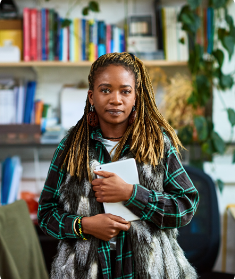 A woman holds a notebook in an office, looking to the camera.